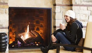 Woman sitting fireside drinking hot beverage at luxury resort